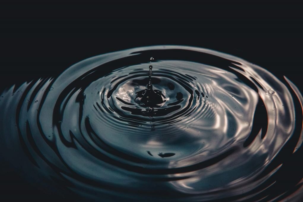 macro photo of water drop creating ripples.