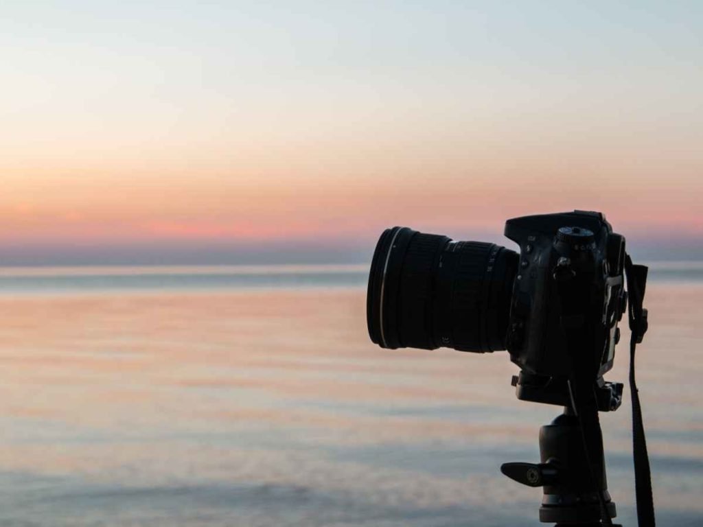 camera on tripod with sunset in the background.