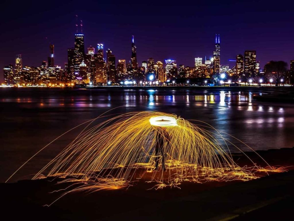 sparkler circle over head with cityscape in the background at night.